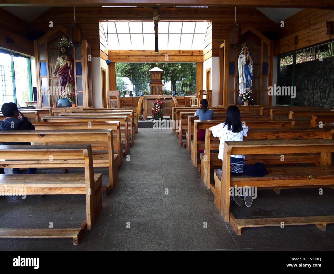BAGUIO CITY, PHILIPPINES - JUNE 7, 2018: Tourists and visitors pray at a chapel at the Lourdes Grotto, a famous tourist spot in Baguio City, Philippin Stock Photo