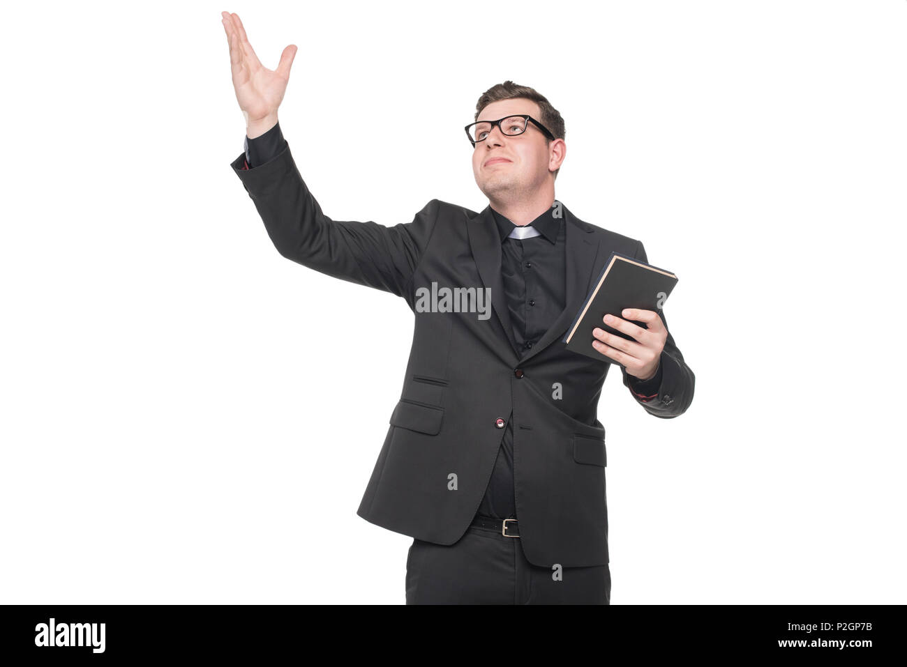 young priest in black suit holding scripture book with hand gesture isolated on white Stock Photo