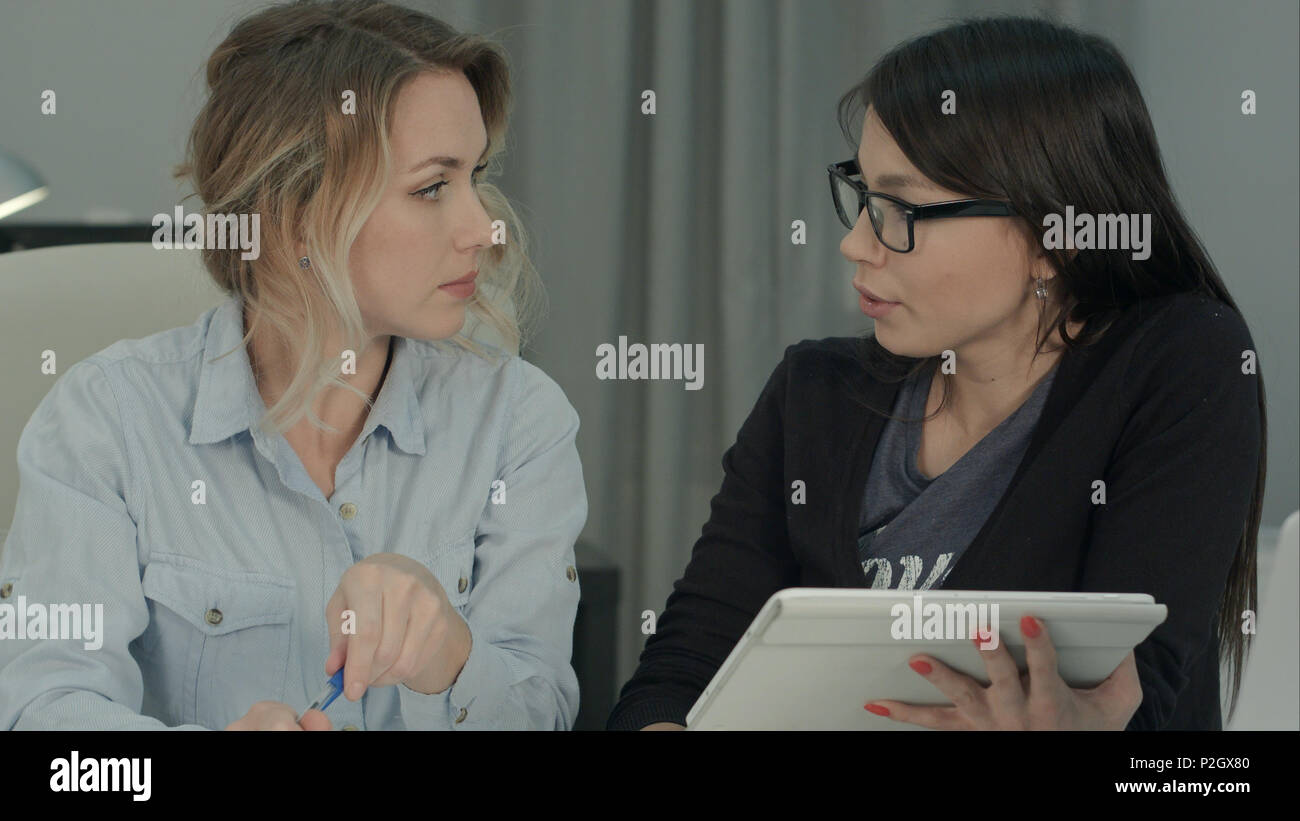 Two female colleagues brainstorming in the office using tablet Stock Photo