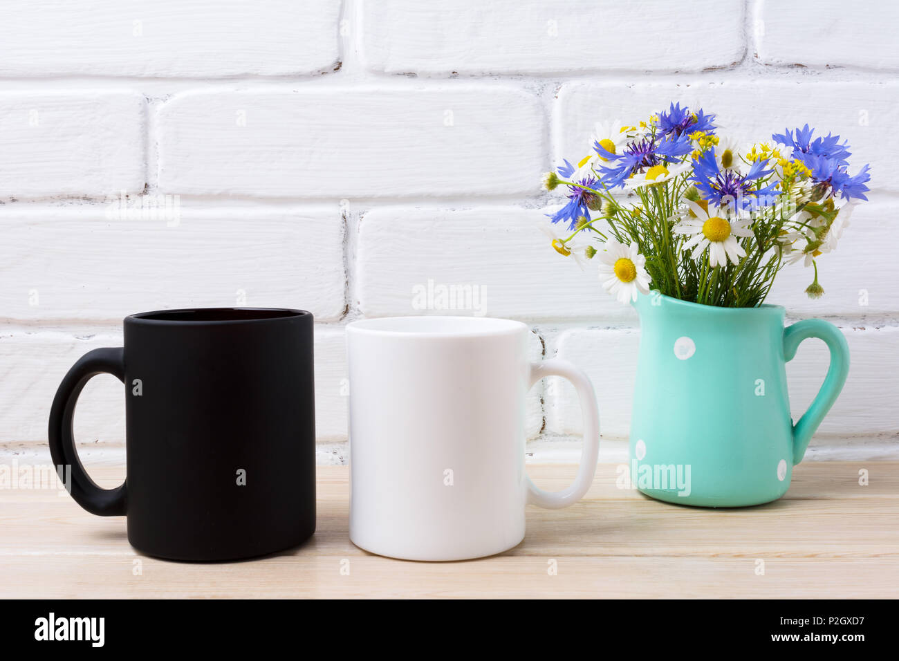 White and black coffe mug mockup with cornflower and daisy in the rustic pitcher vase.  Empty mug mock up for design promotion. Stock Photo