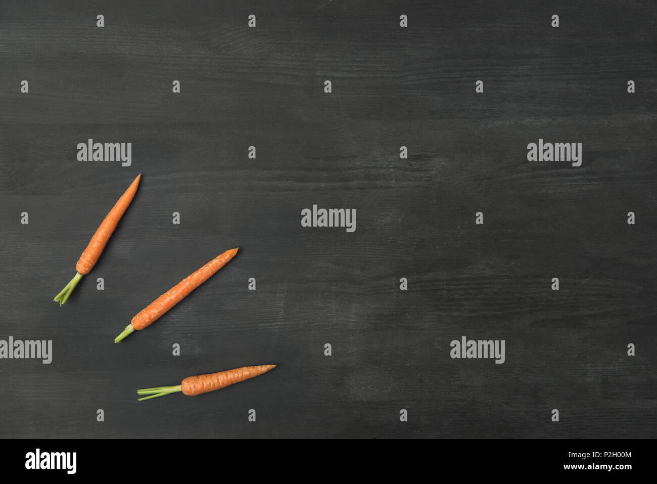 top view of arranged ripe carrots on dark surface Stock Photo