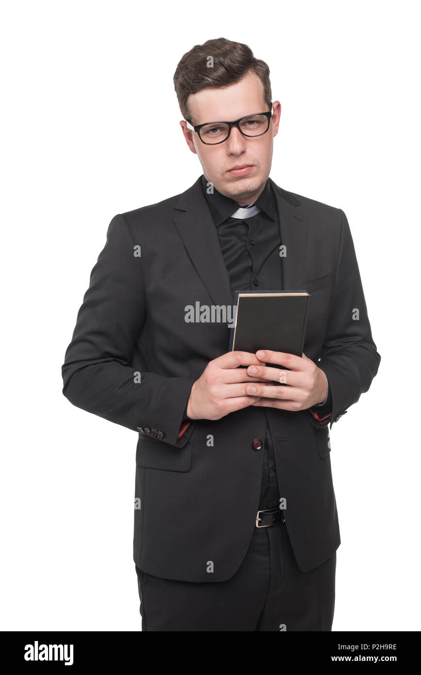 young priest in black suit holding scripture book and looking at camera isolated on white Stock Photo
