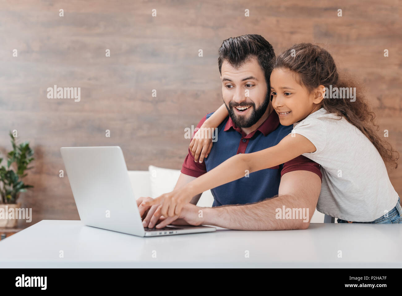 smiling father using laptop while happy daughter hugging him and ...