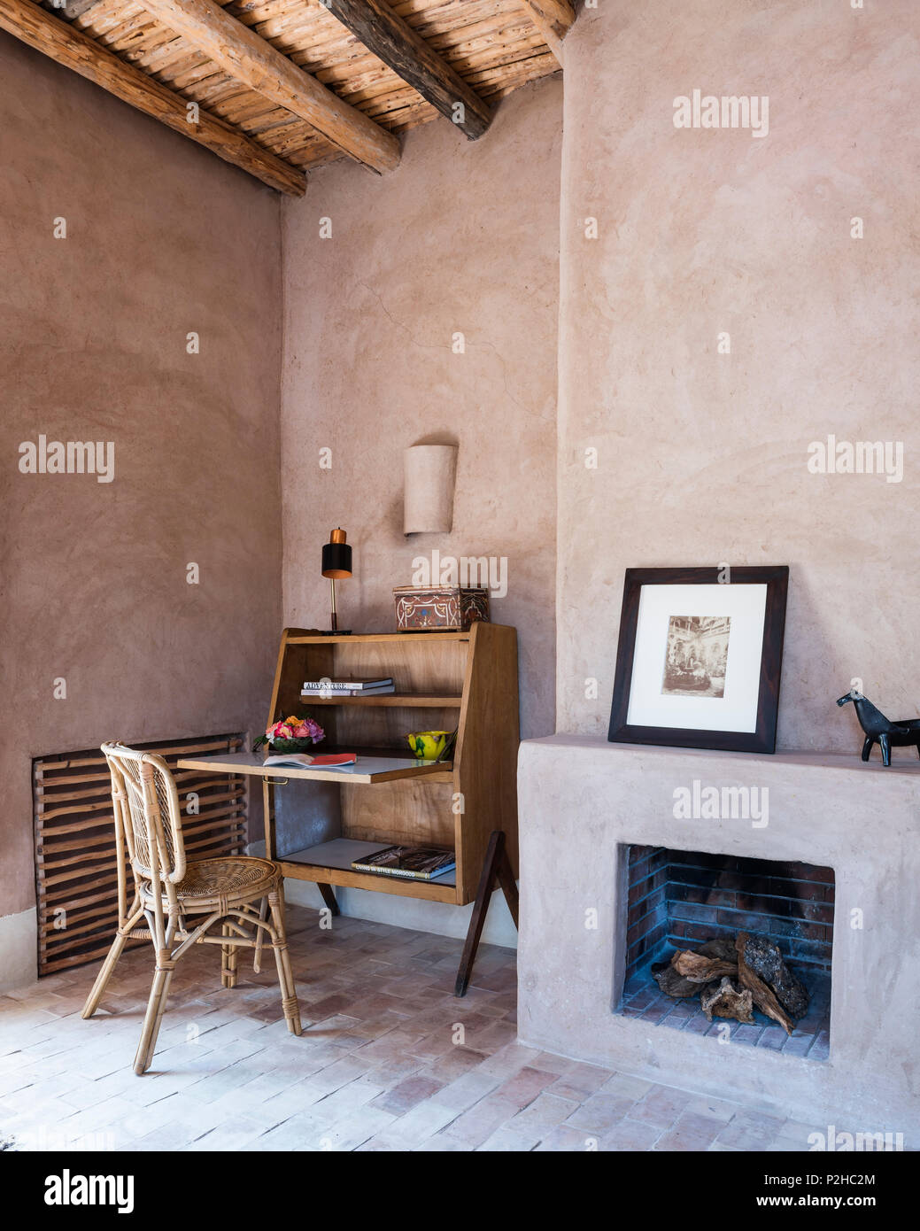 Open Fire And Small 1950s Bureau In Bedroom With Earth Walls