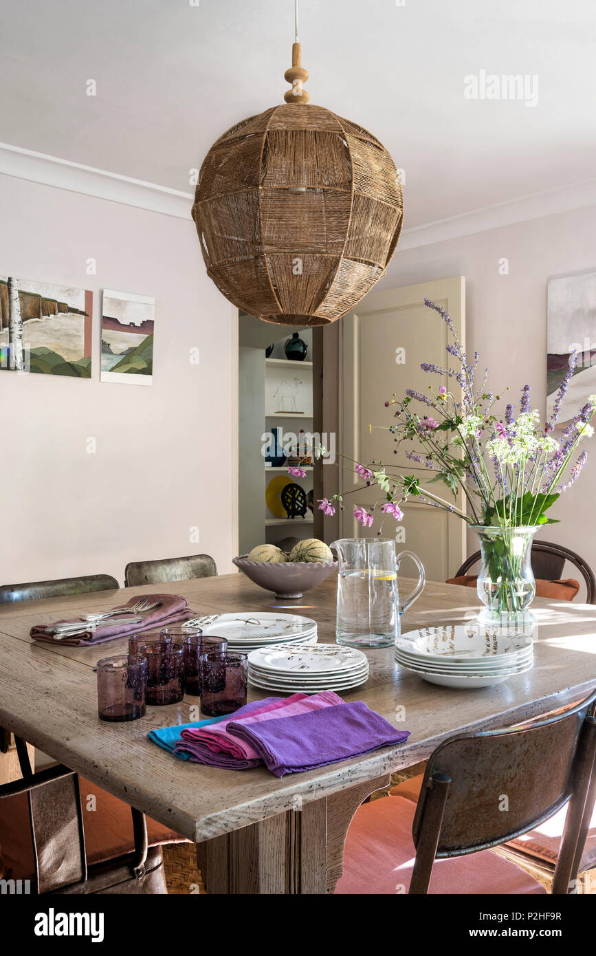 Pendant shade above dining table with purple glassware in 18th century Luberon home. Stock Photo