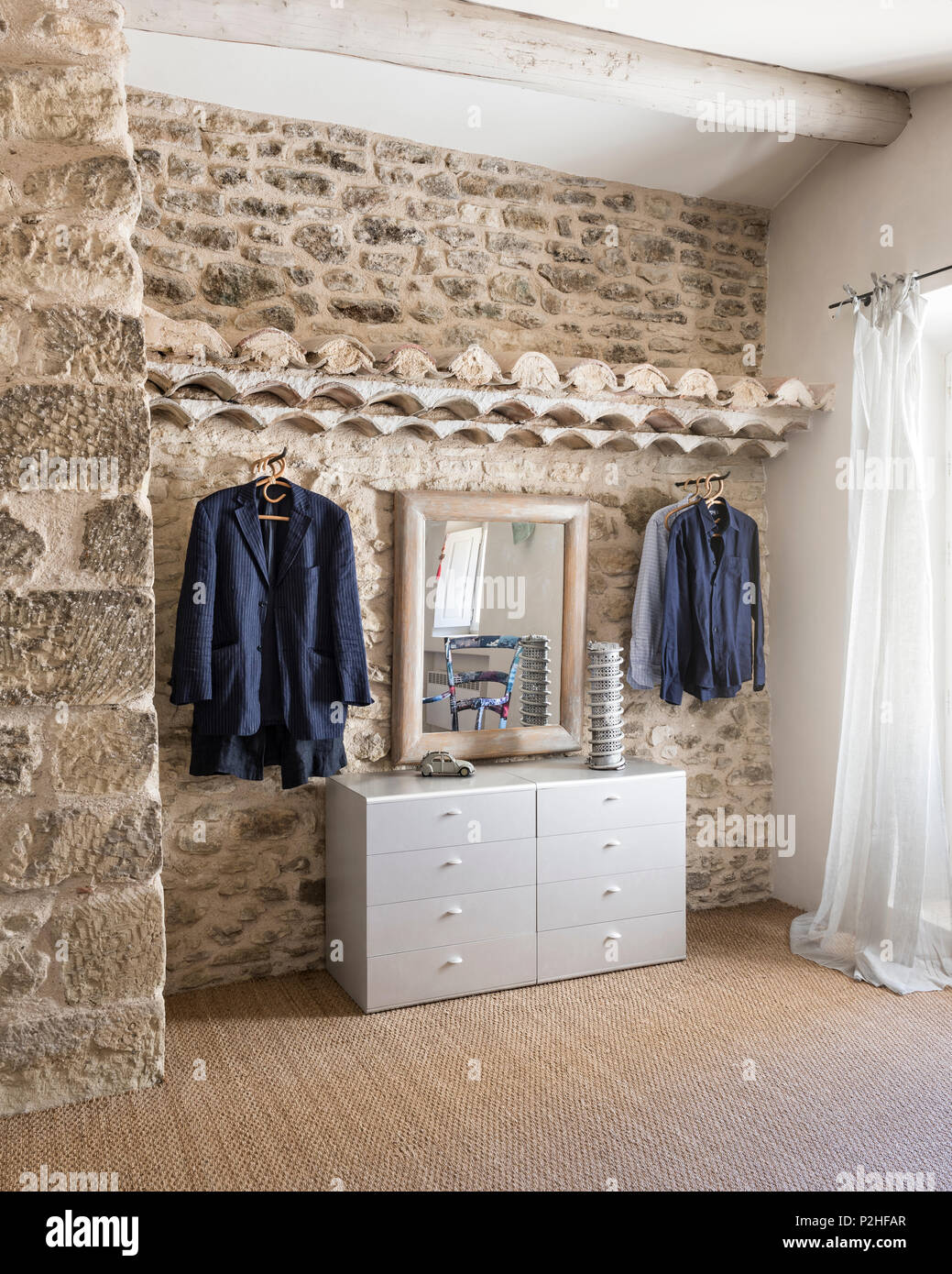 Clothes hand in exposed stone bedroom of 18th century Luberon farmhouse Stock Photo