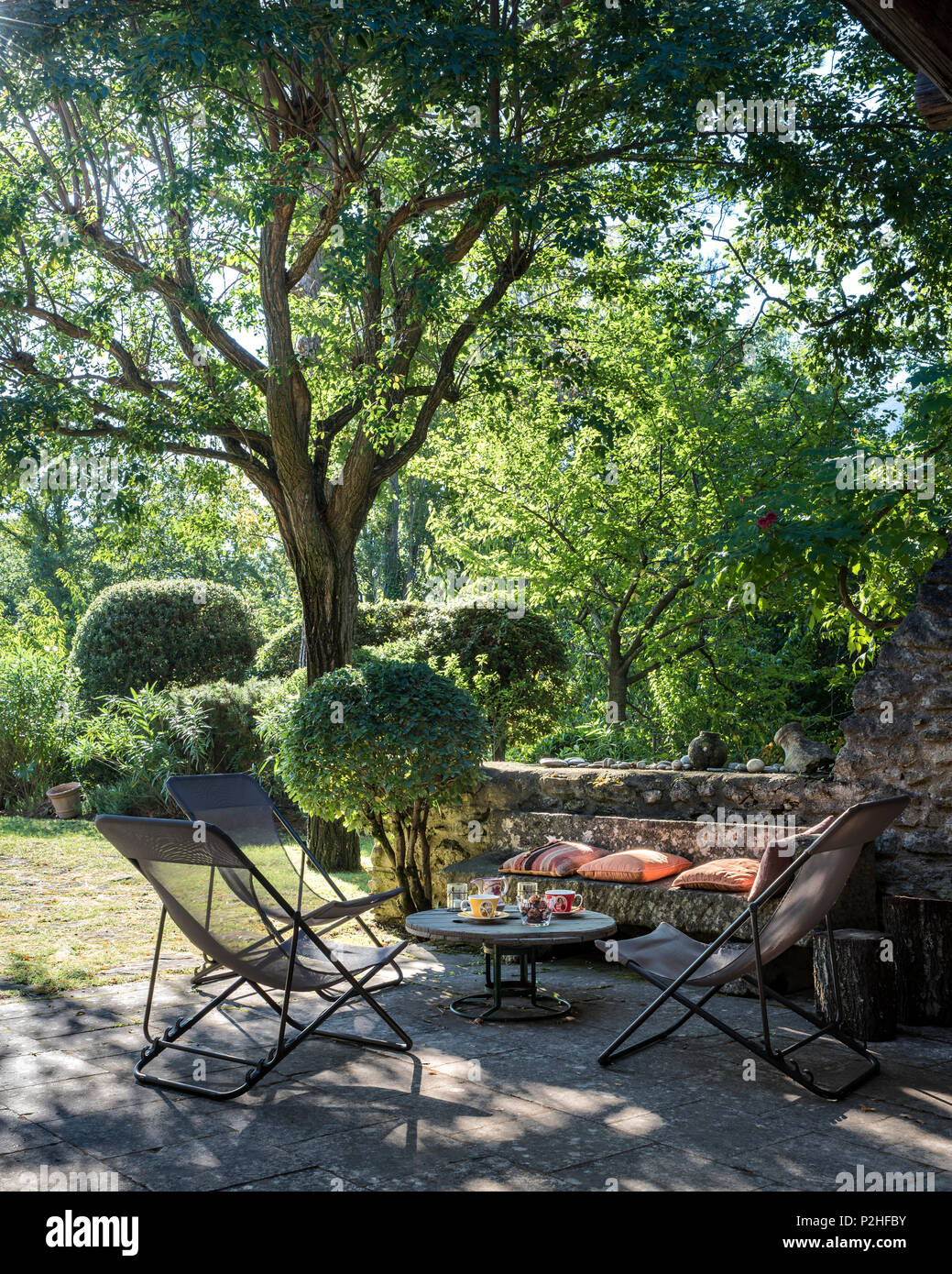 Deck chairs and table in shade of tree in, Luberon. Stock Photo