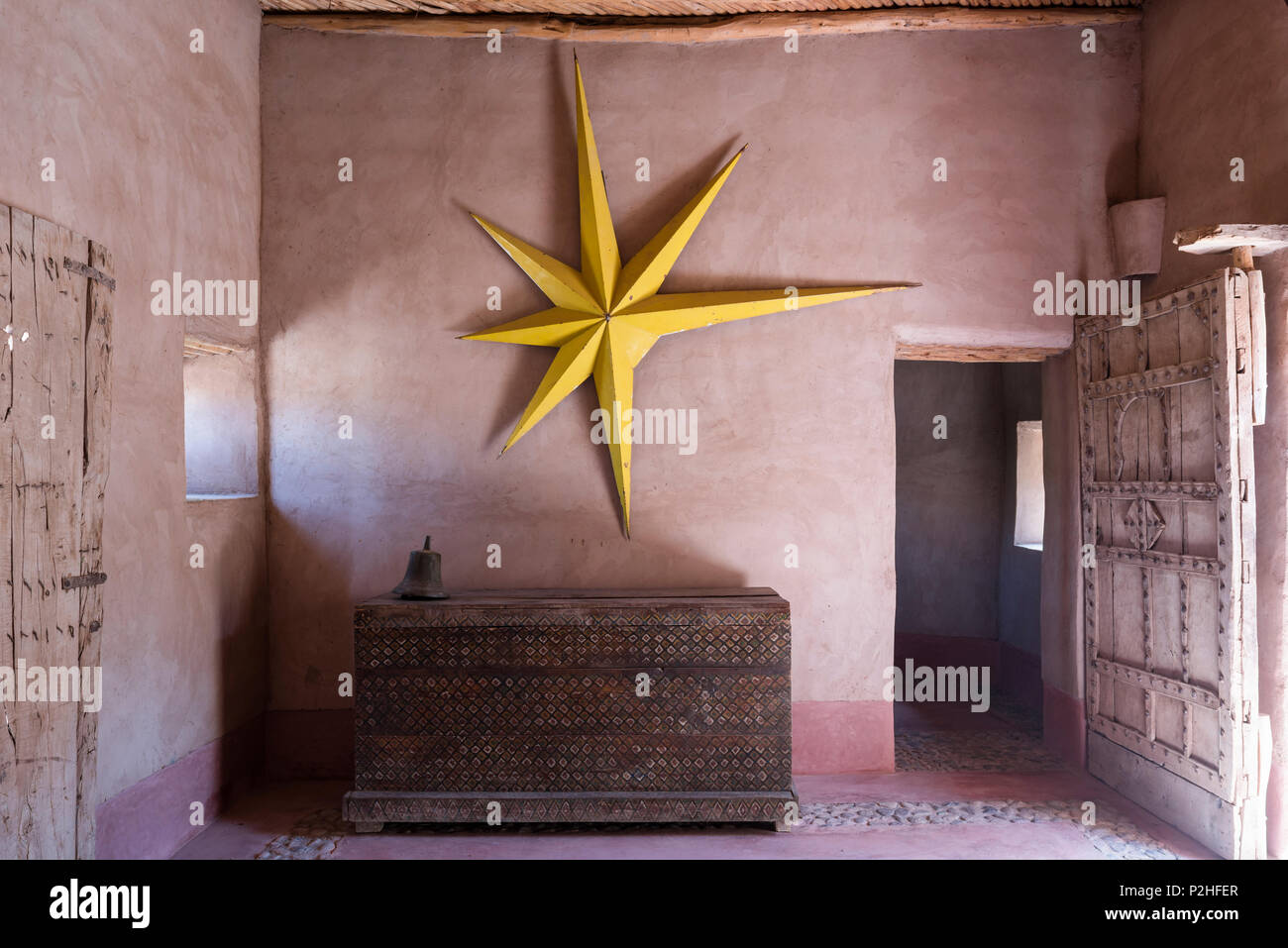 Large yellow star hung on earth wall in entrance hall of Berber Lodge with antique wooden chest and studded panelled door Stock Photo
