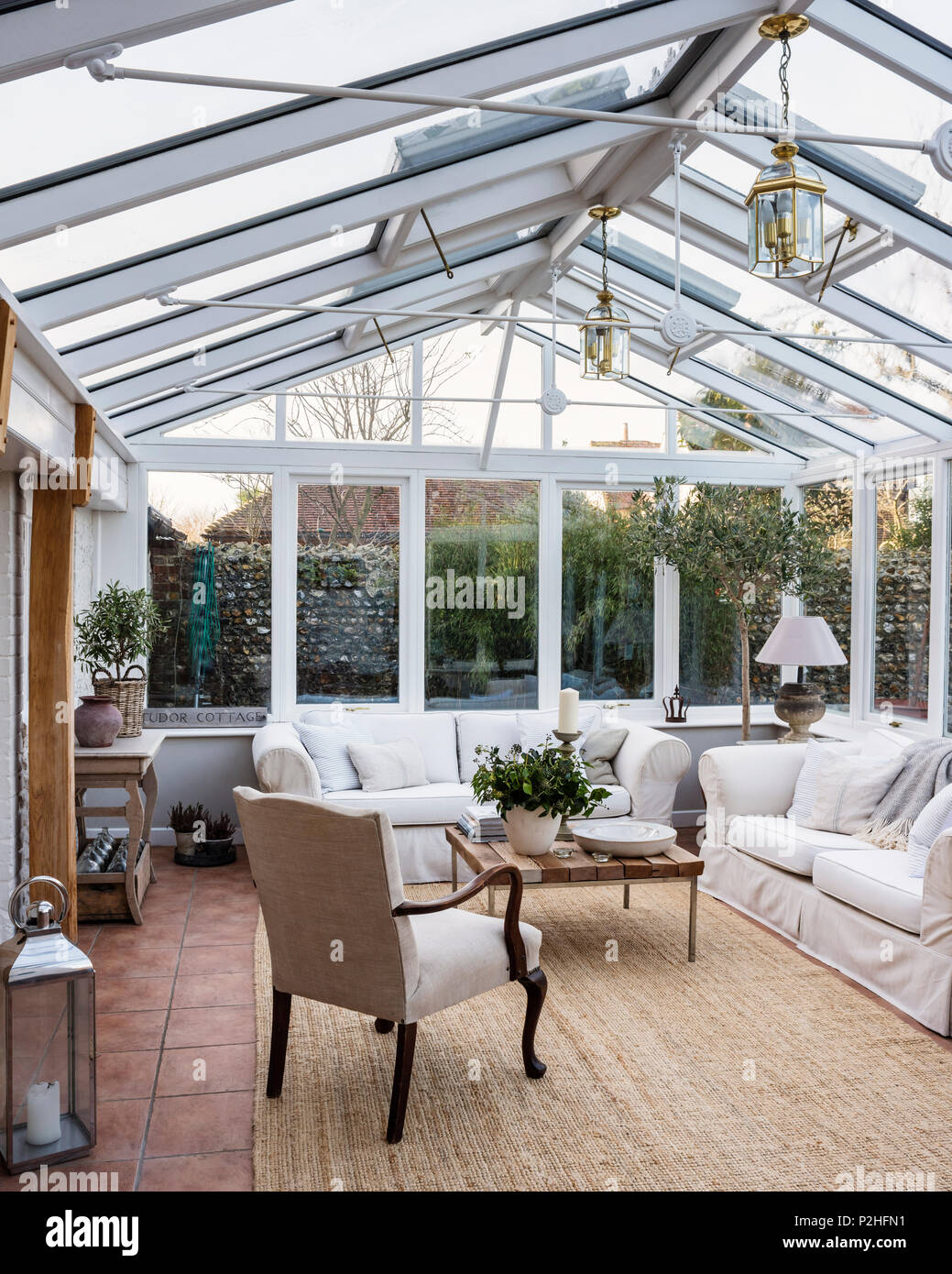 Spacious conservatory with antique armchair and lanterns sourced from Heritage Antiques. Stock Photo
