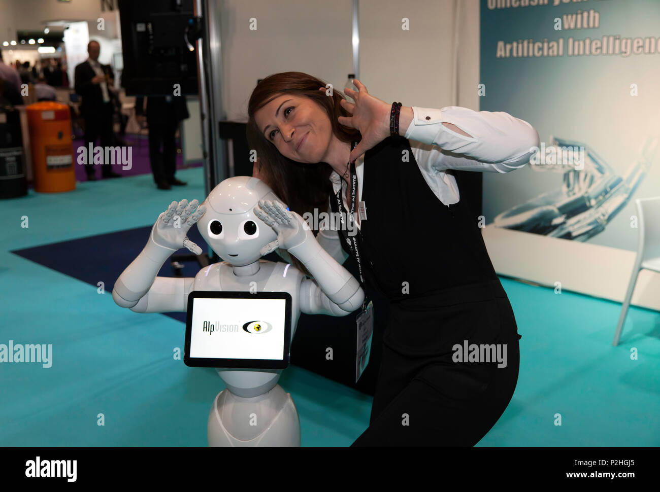 Pepper, a humanoid social robot, poses for a selfie with a  female delegate on the AlpVision stand at the 2018 AI Summit, Stock Photo