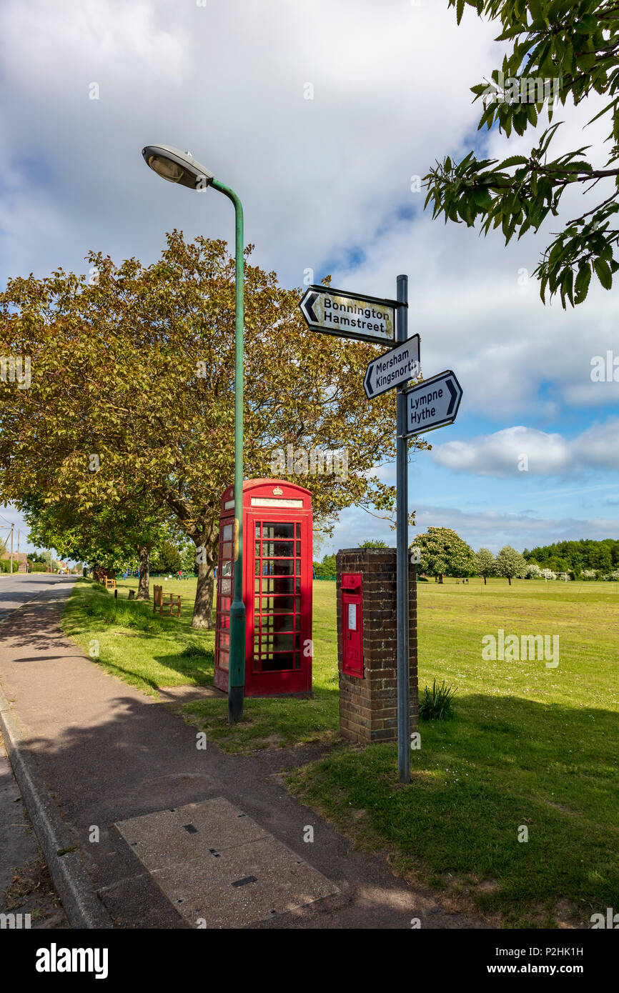 Aldington crossroads, and playing field with tradirional red post and telephone boxes. Sign to Bilsington, Hythe, Lympne and Kingsnorth, Mersham and Hamstreet, Kent Stock Photo