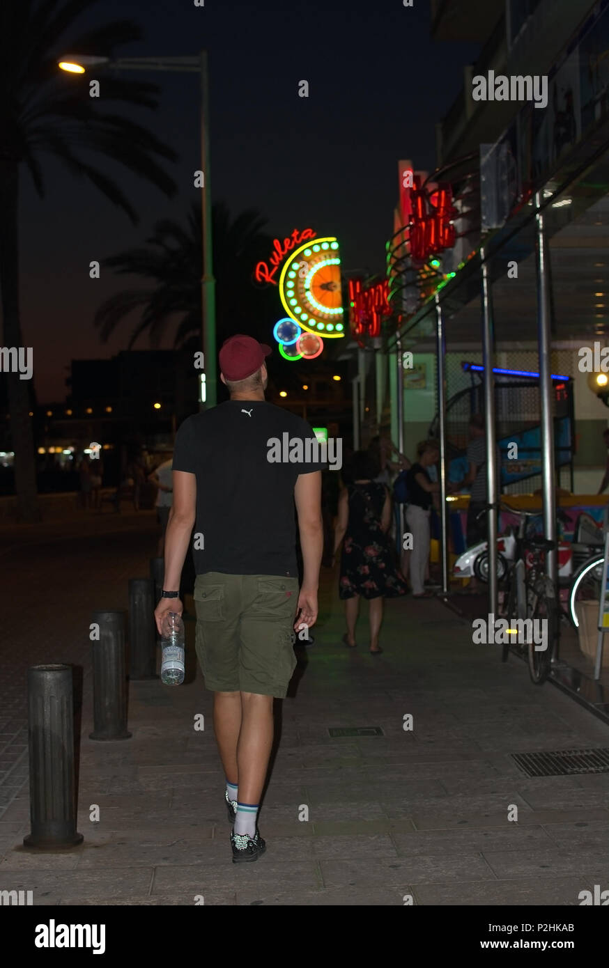 CAN PASTILLA, MAJORCA, BALEARIC ISLANDS, SPAIN - JULY 27, 2015: Can Pastilla night scenes young man walking from behind on July 27, 2015 in Mallorca,  Stock Photo