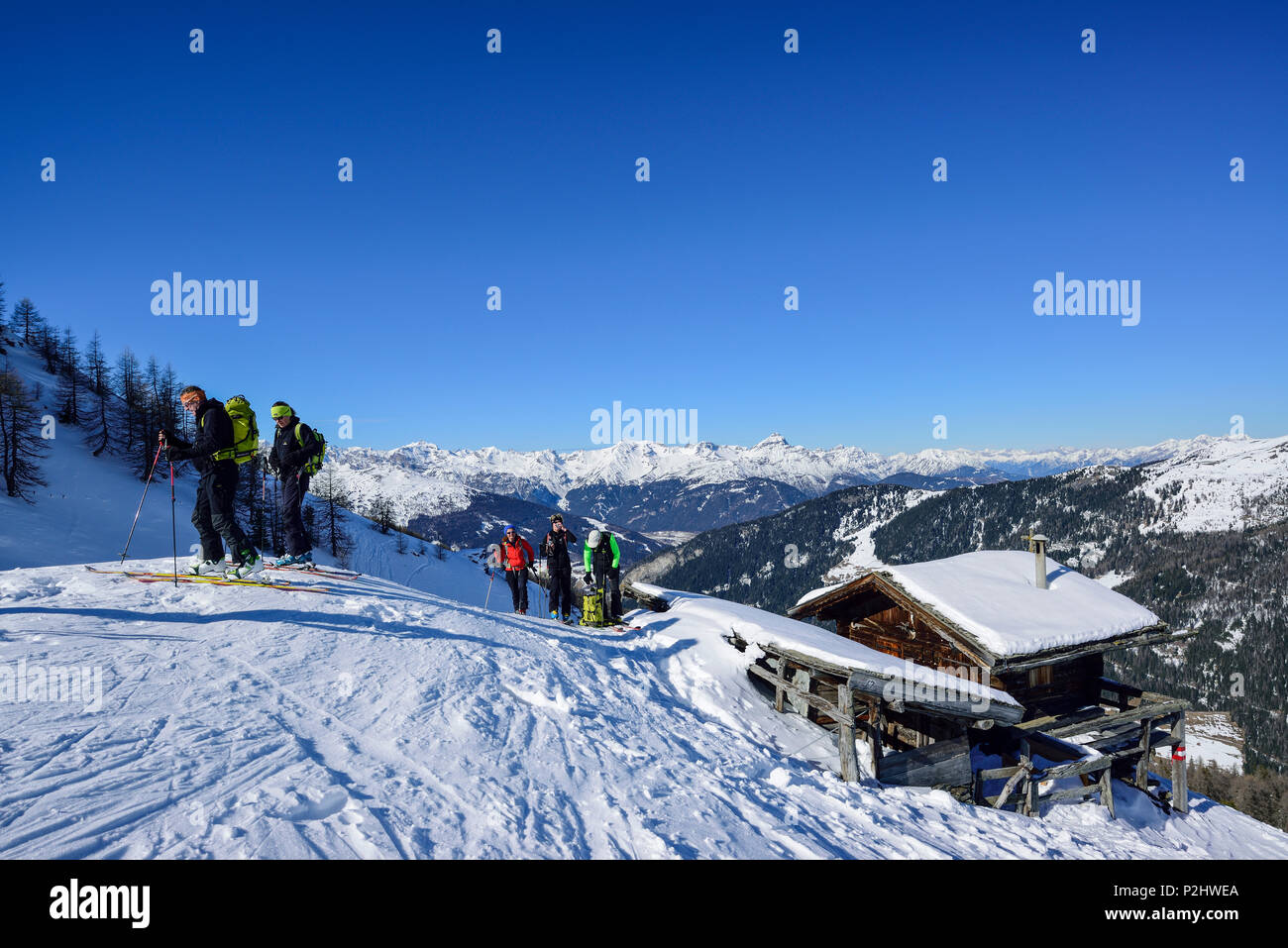 Several persons back-country skiing having a break at an alpine hut, Stubai Alps in the background, Gammerspitze, valley of Schm Stock Photo