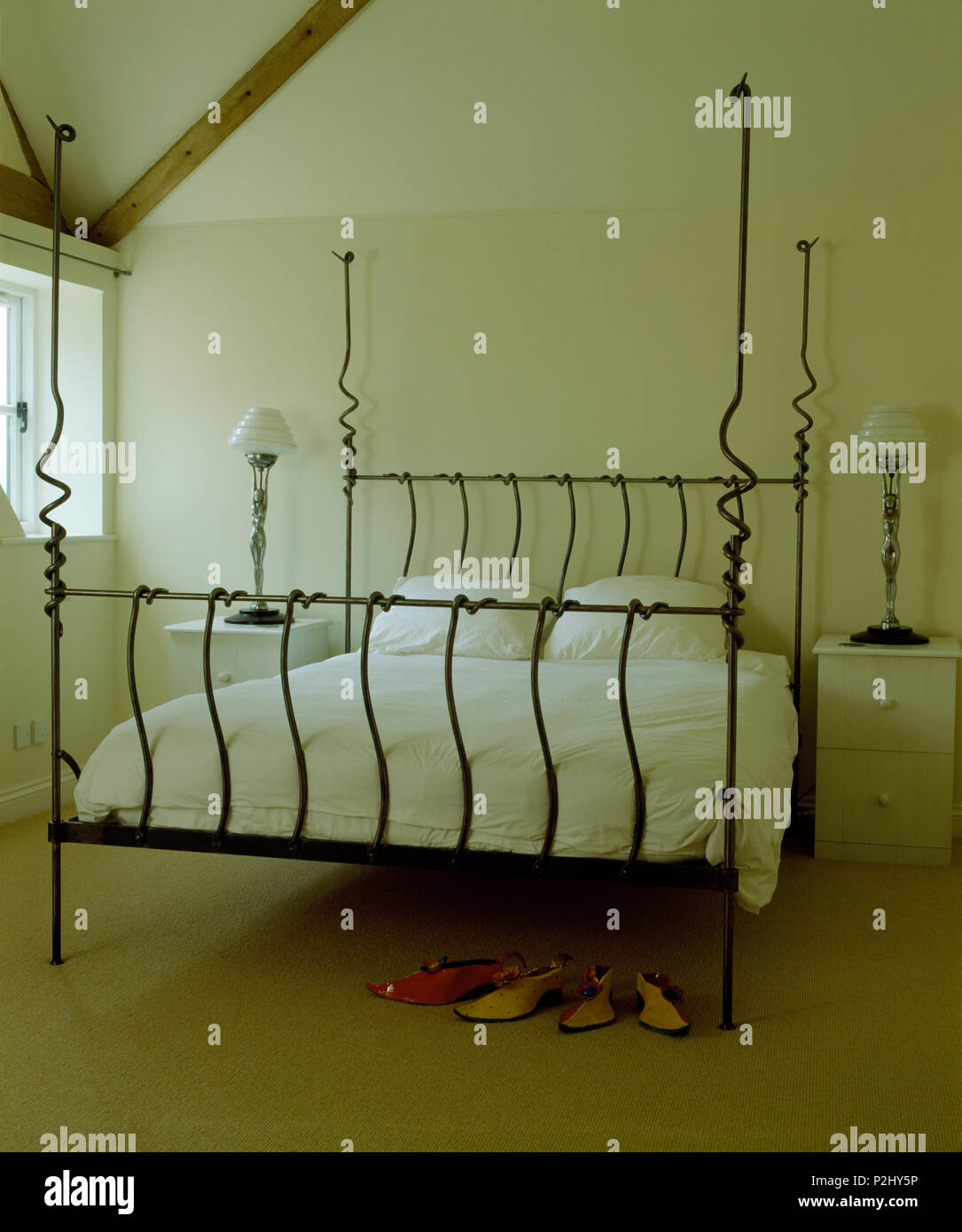 White bedlinen on designer wrought iron bed in modern white bedroom Stock Photo