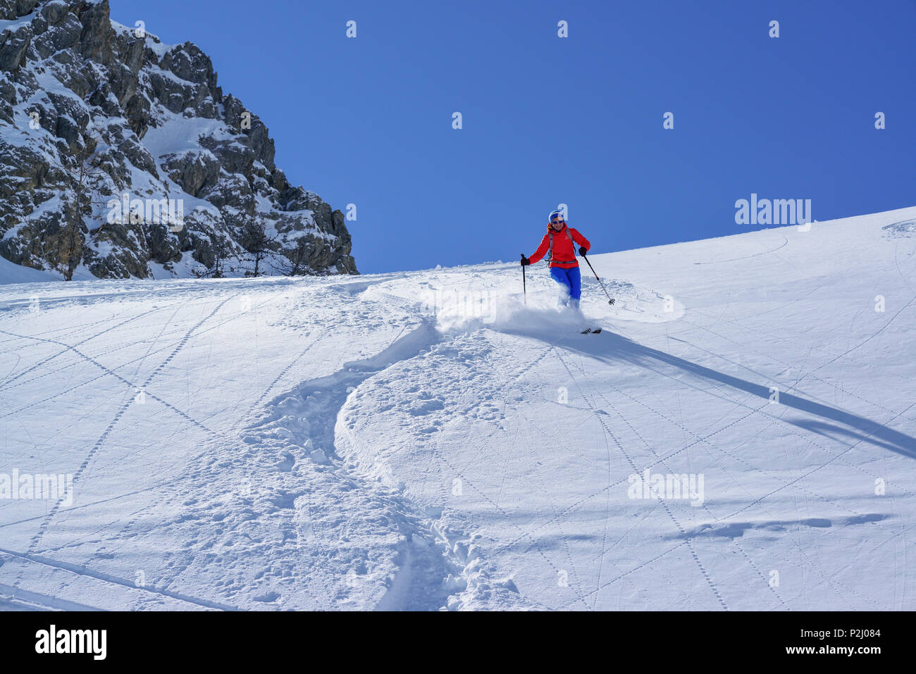 Woman back-country skiing downhill through powder snow from Passo Croce, Passo Croce, Valle Maira, Cottian Alps, Piedmont, Italy Stock Photo