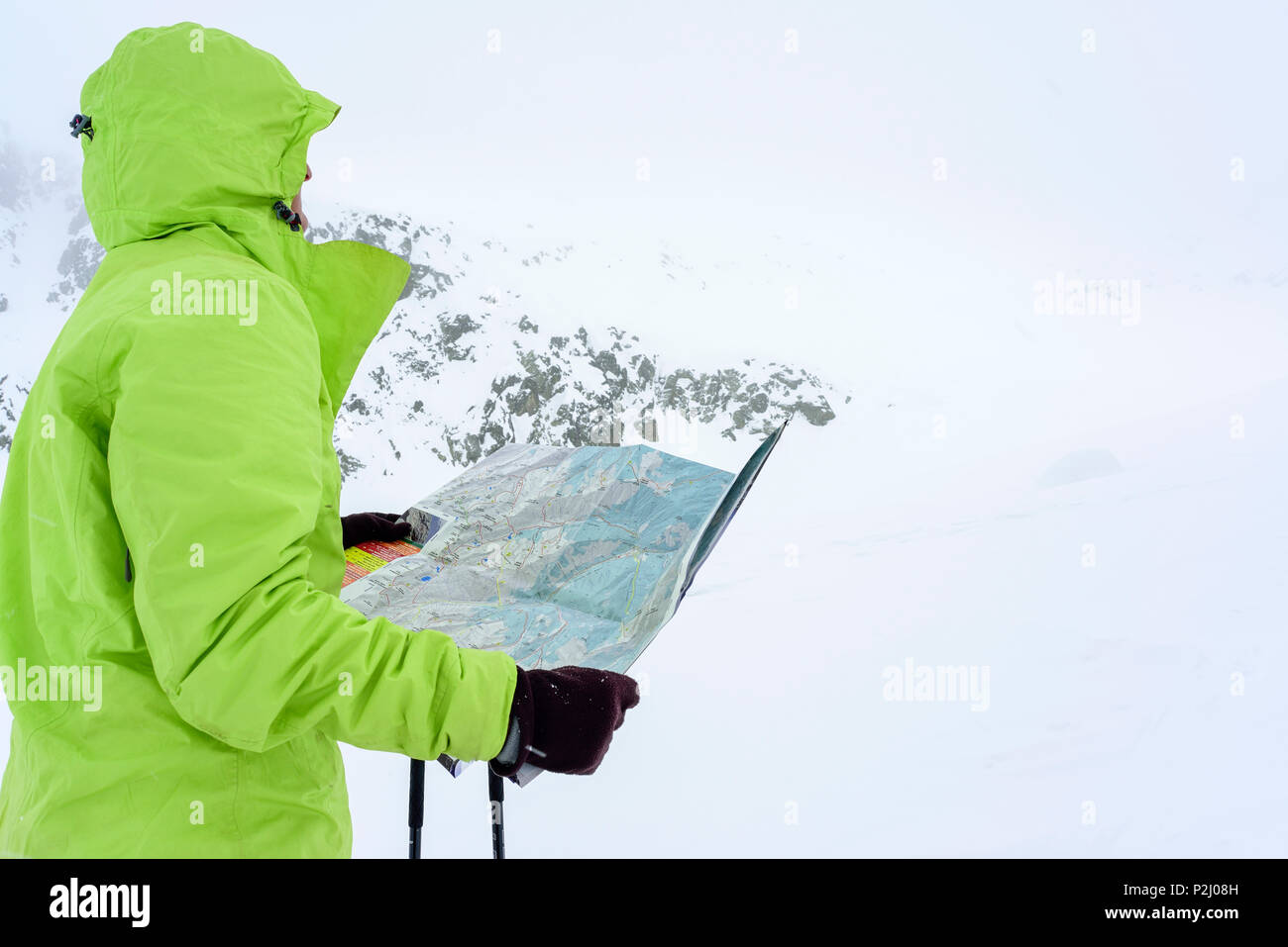 Woman back-country skiing studying map during bad weather, Serriera di Pignal, Valle Stura, Cottian Alps, Piedmont, Italy Stock Photo