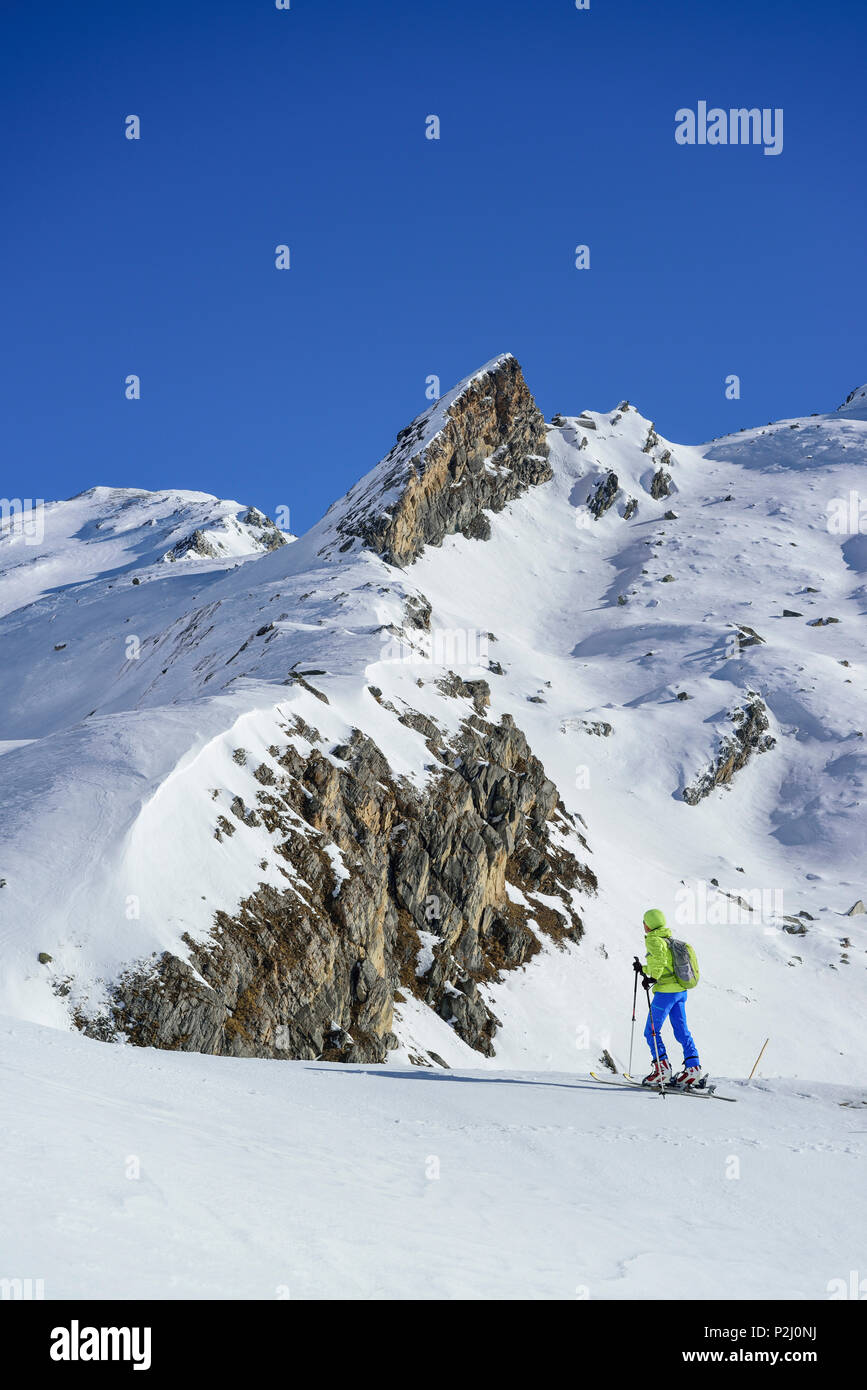 Woman back-country skiing ascending towards Monte Salza, spire in the background, Monte Salza, Valle Varaita, Cottian Alps, Pied Stock Photo