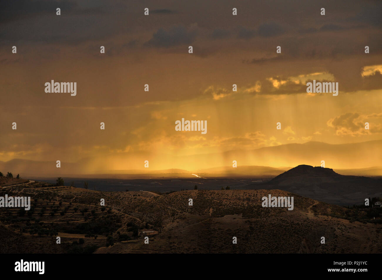 yellow sunrays breaking through clouds, thunderstorm near Granada, seen from Monachil at the foothills of the Sierra Nevada, And Stock Photo