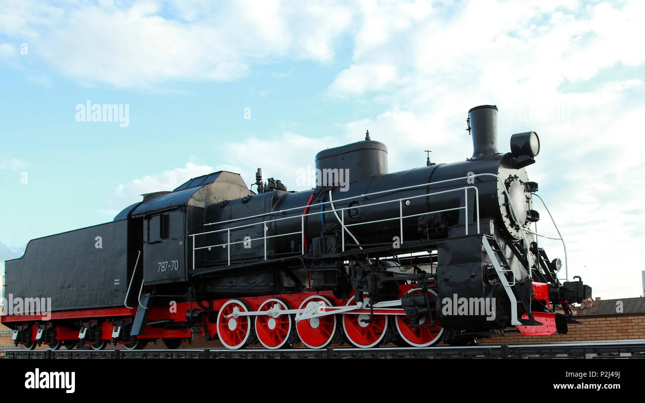 Black vintage steam locomotive with red wheels on the railway. Stock Photo