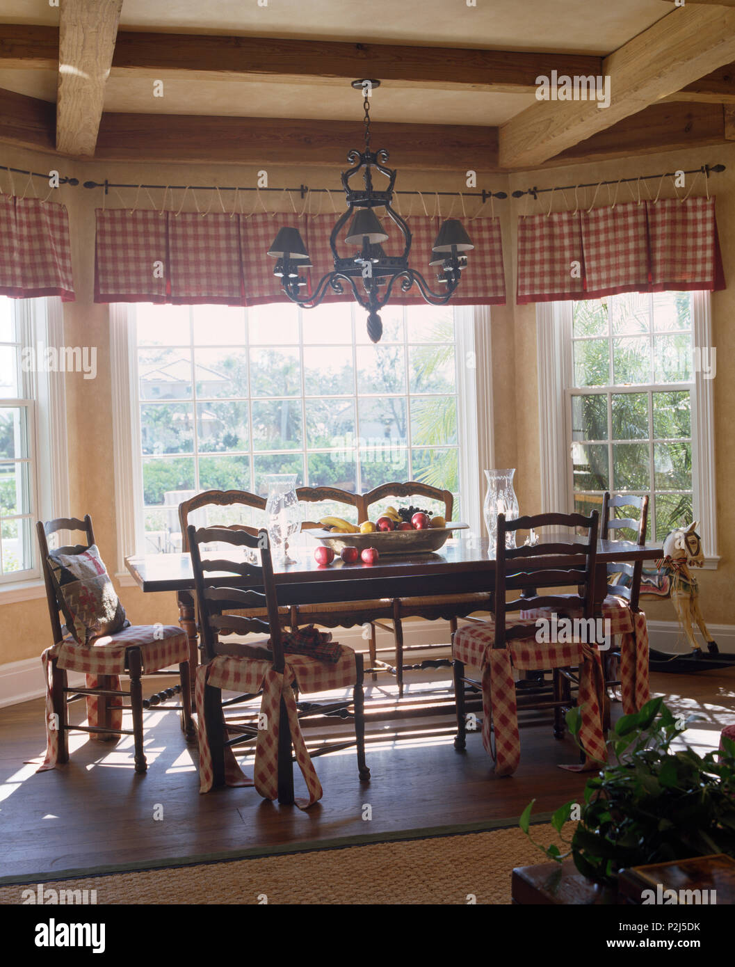 Ladder back chairs with red checked cushions at simple table in country dining room Stock Photo