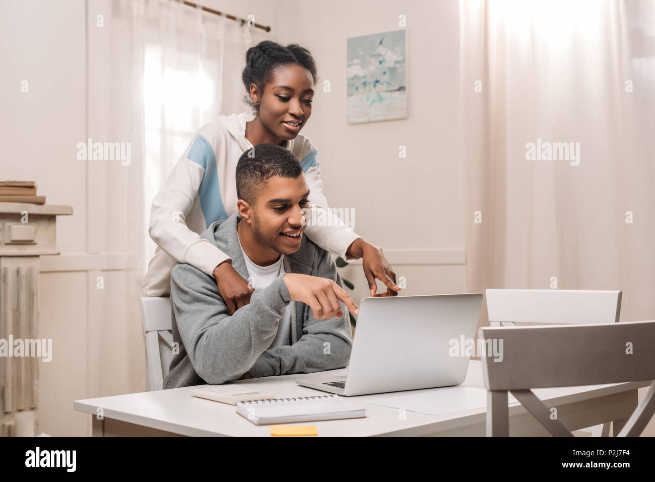 happy african american couple using laptop and pointing on screen at ...