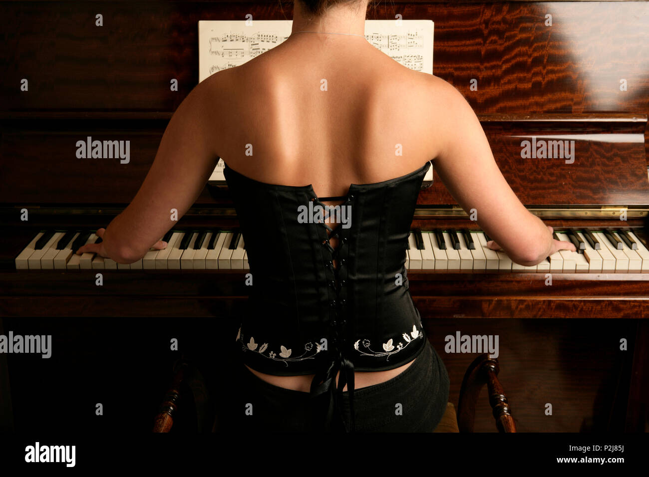 young woman playing the piano back view. Stock Photo