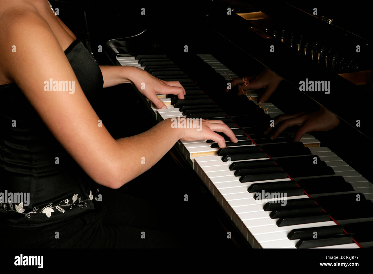 young woman playing the piano back view. Stock Photo
