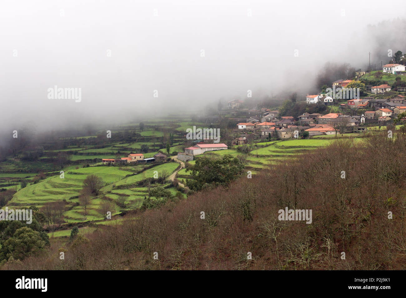 Paredes village in mist / low cloud, traditional Portuguese village with stepped fields. Stock Photo