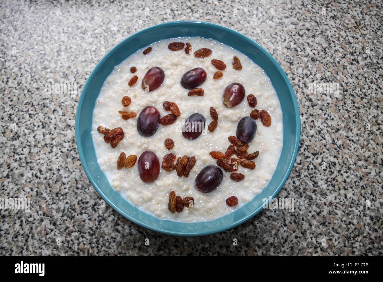 A bowl of porridge with red grapes and sultanas added Stock Photo