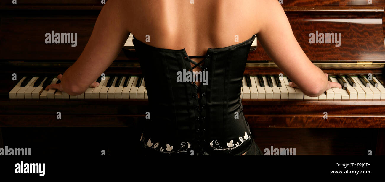 Young woman in concert dress playing the piano Stock Photo