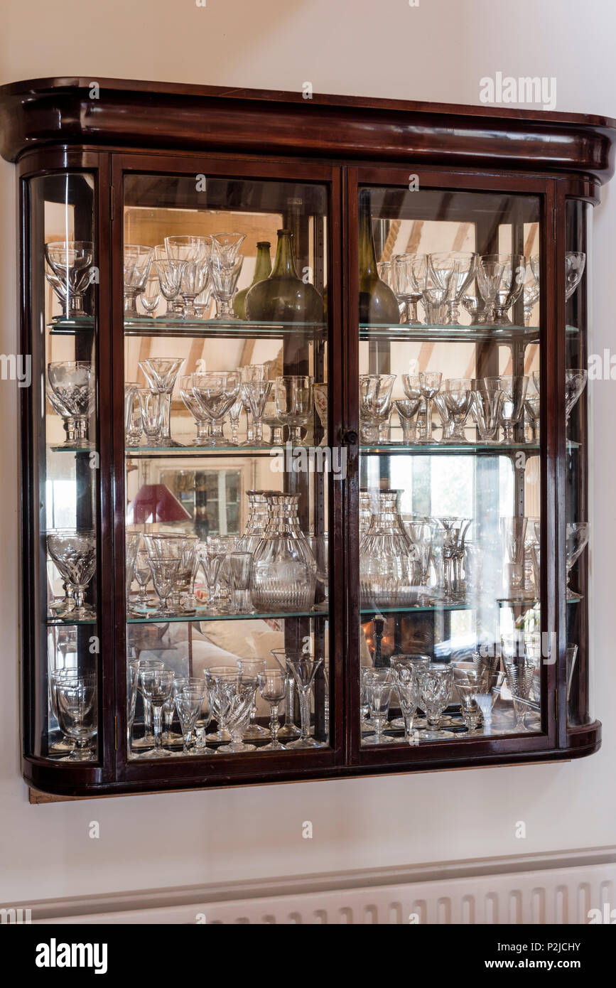 Early 20th century display cabinet with a collection of antique decanters and glasses, Sussex, UK Stock Photo