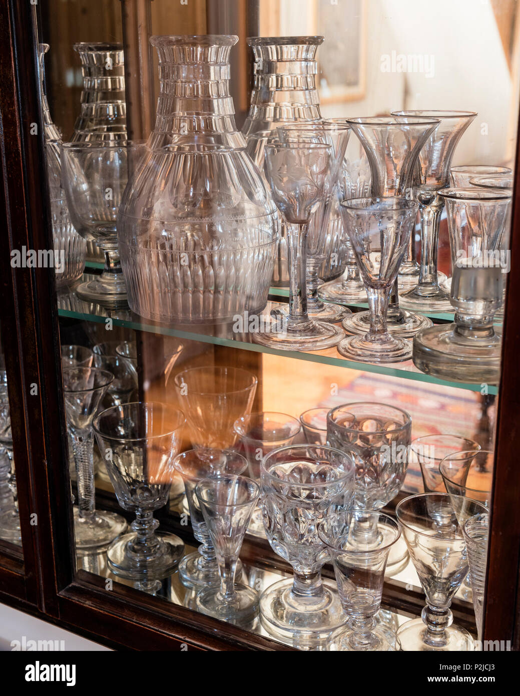 Early 20th century display cabinet with a collection of antique decanters and glasses, Sussex, UK Stock Photo