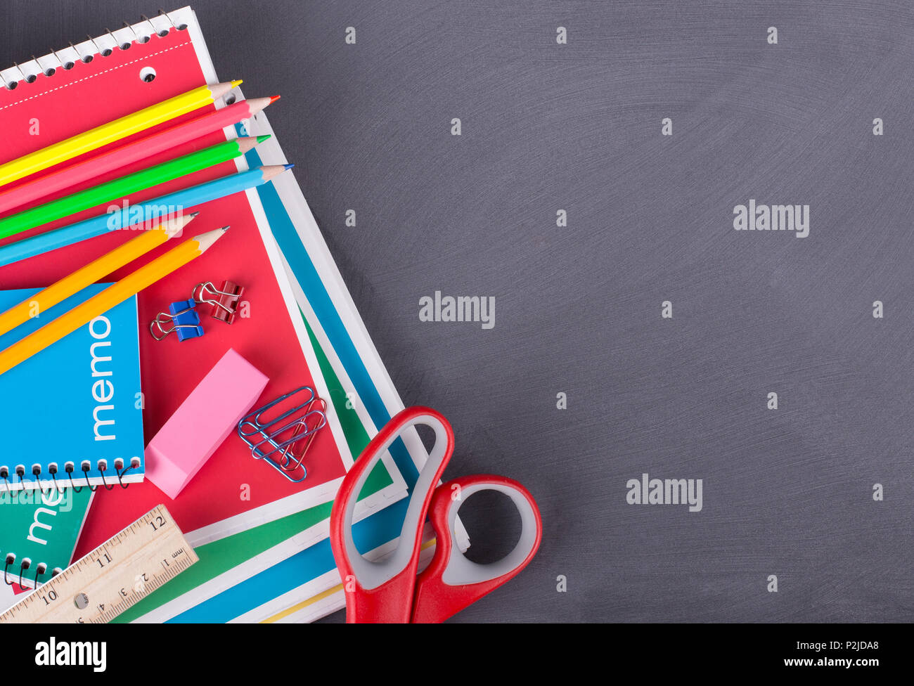 Overhead view of an assortment of school supplies on a blackboard background with copy space Stock Photo