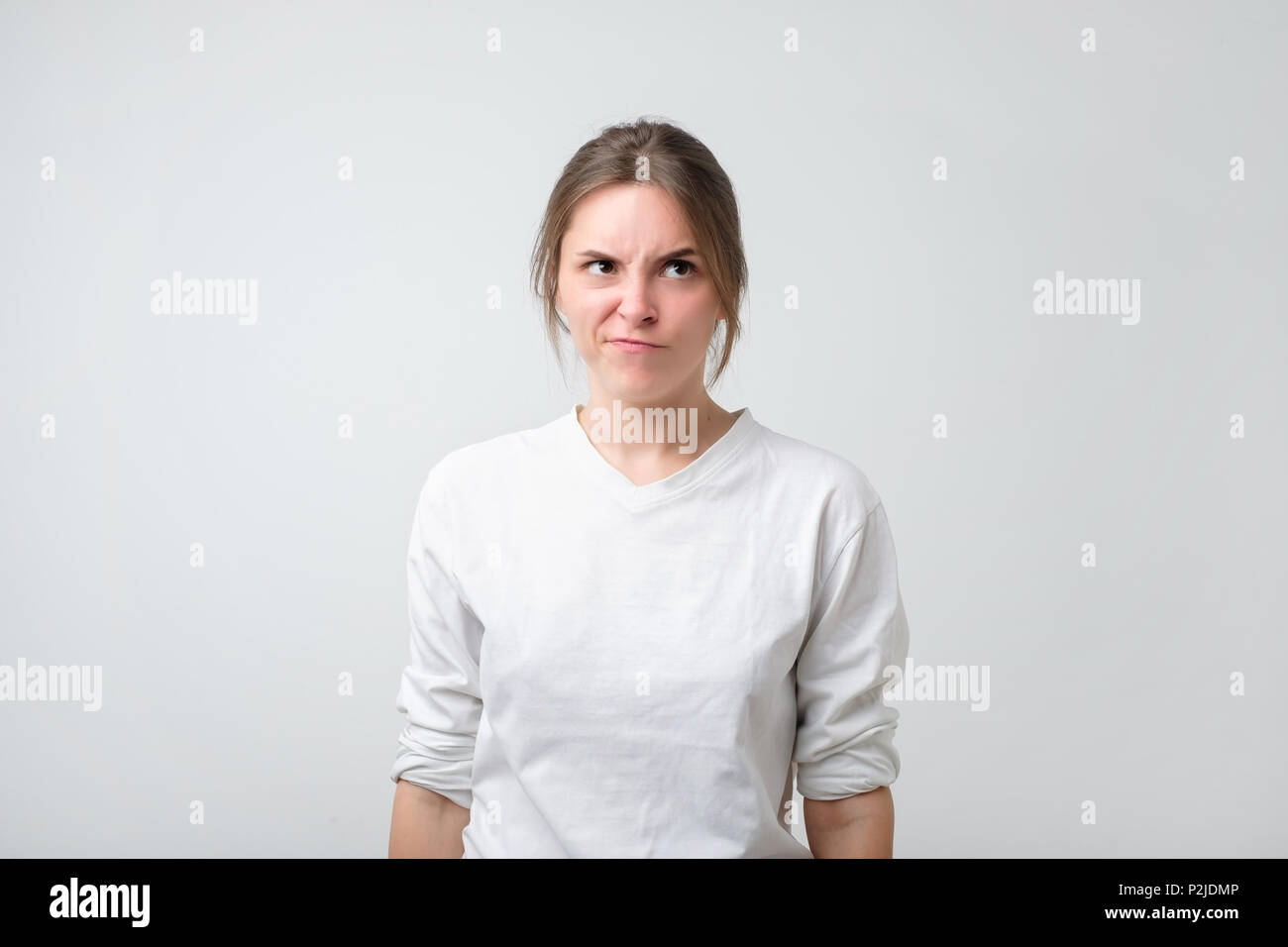 Portrait of an upset unsatisfied european woman. She is frowning her nose in irritated mood. Negative facial emotion Stock Photo