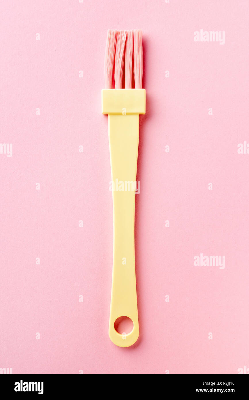 Yellow and pink pastry brush isolated on pink background, from above Stock Photo
