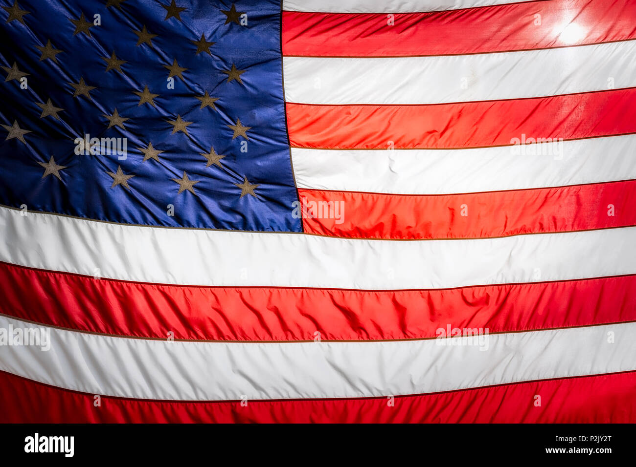 The sun shining behind the stripes of an American flag. Stock Photo