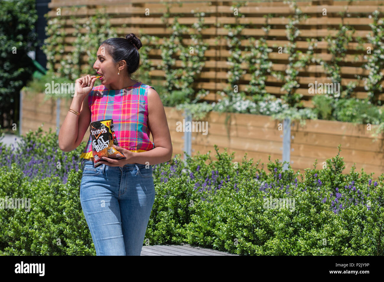 Woman eating Doritos outside Stock Photo - Alamy