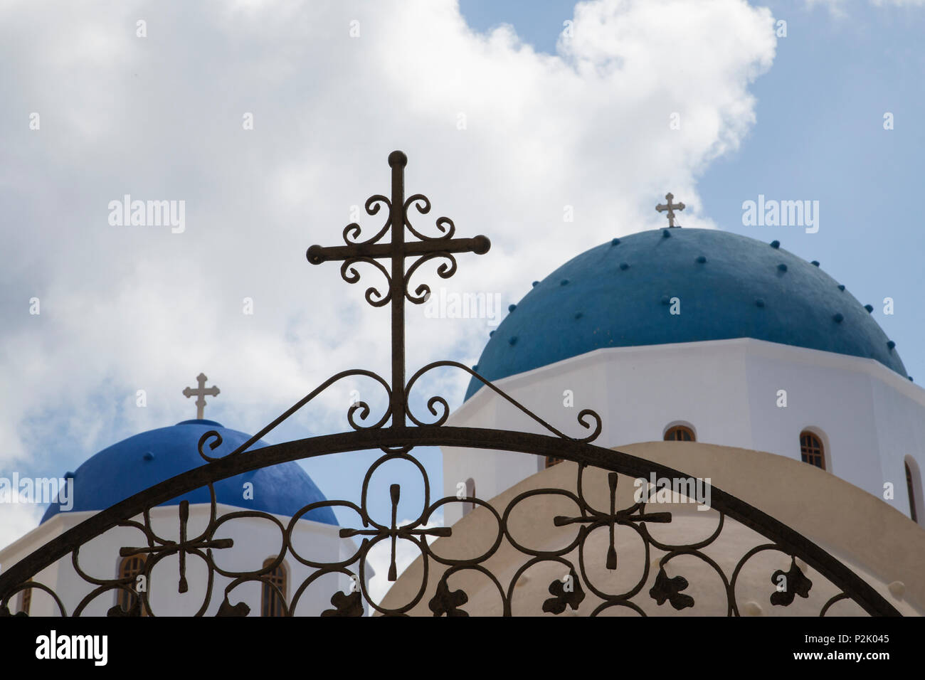 wrought-iron gate with cross in front of blue painted domed church chapel on greek isalnd santorin Stock Photo