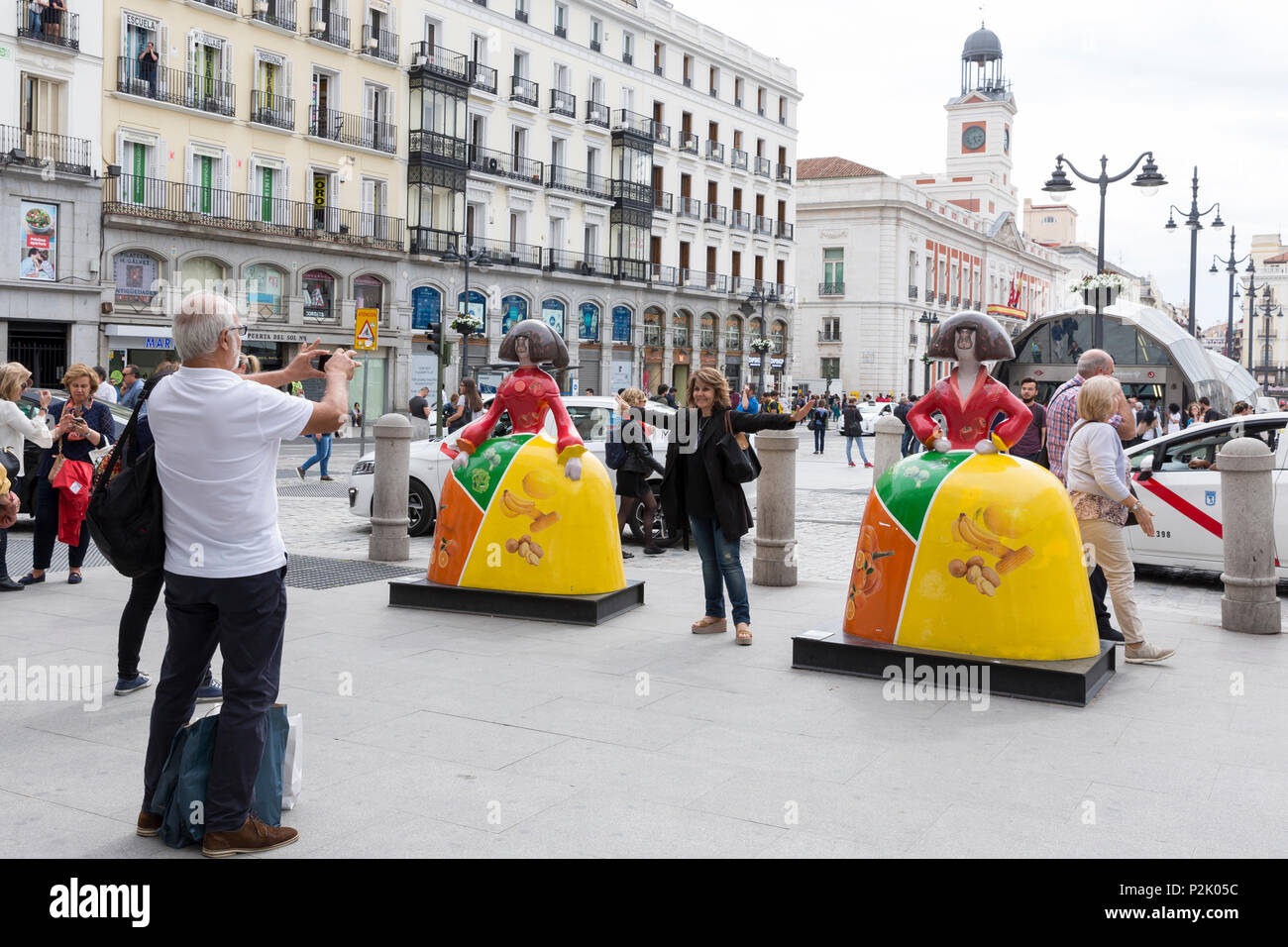 Madrid, Spain: Madrid, Spain: Tourists pose with 'Menina' sculptures at Puerta del Sol. The busy public square in the heart of Madrid is the center of Stock Photo