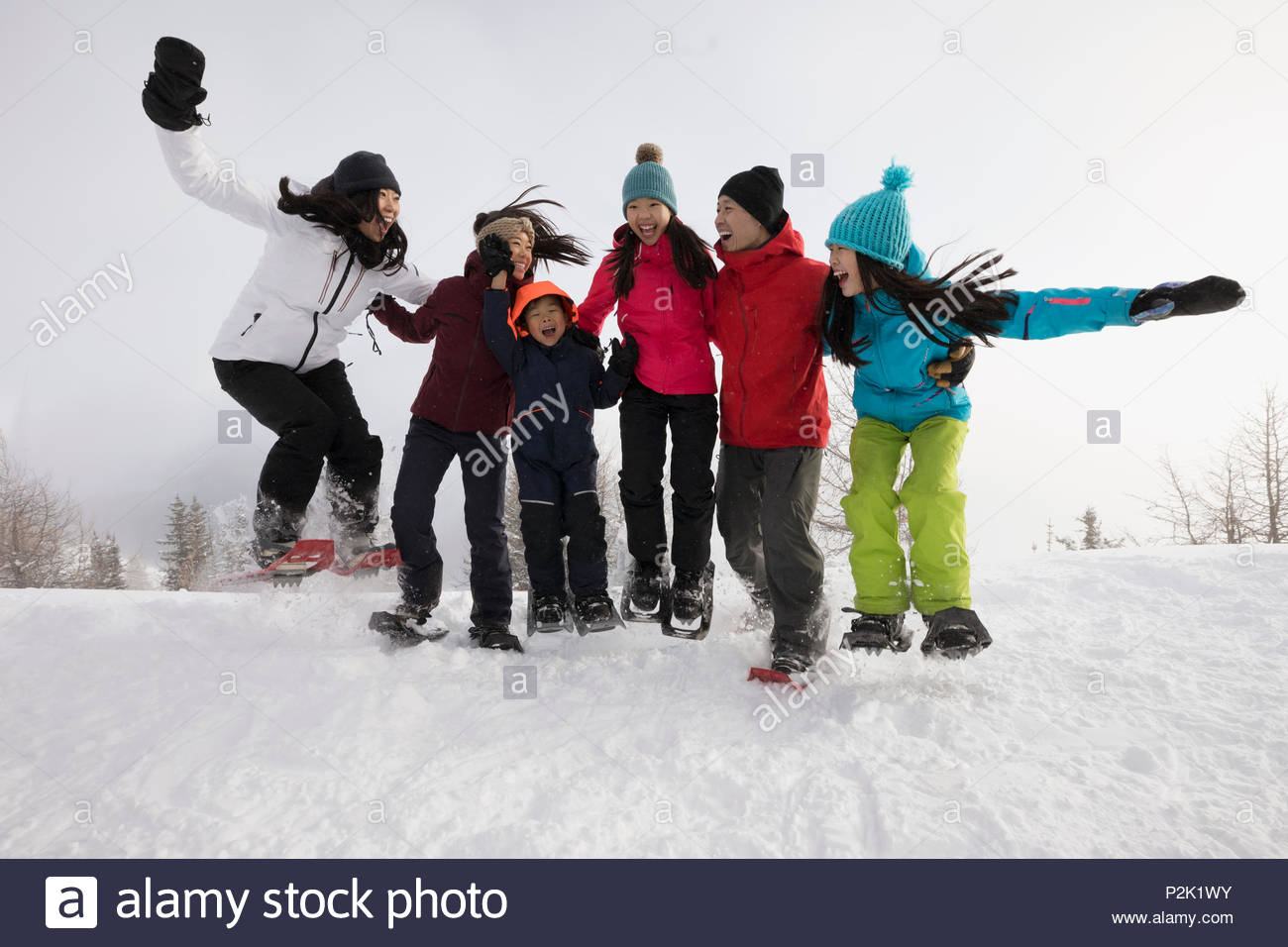 Playful, energetic family snowshoers jumping in snow Stock Photo