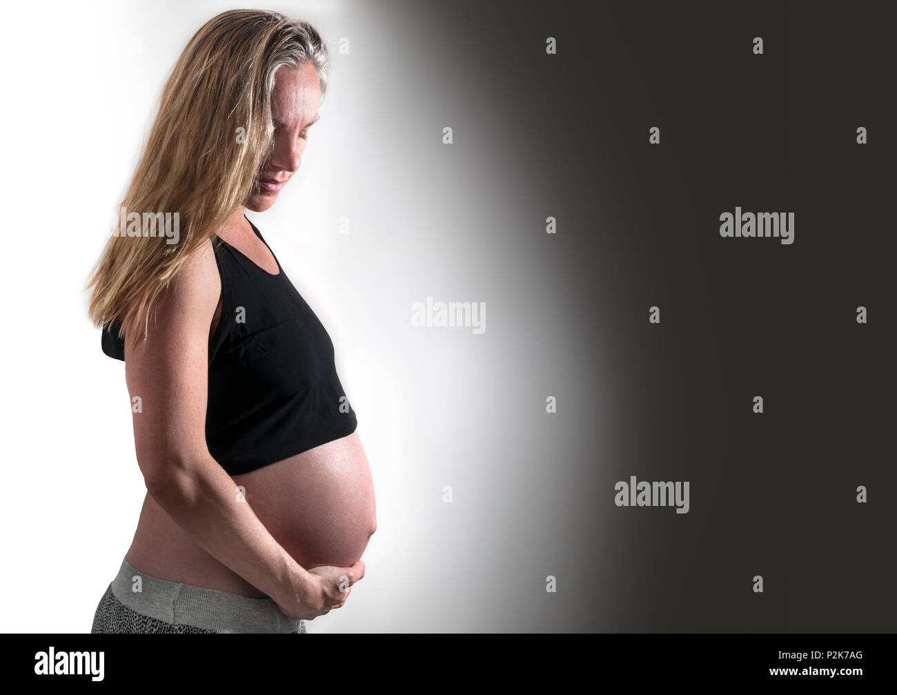 Pregnant woman posing with her belly exposed. Stock Photo