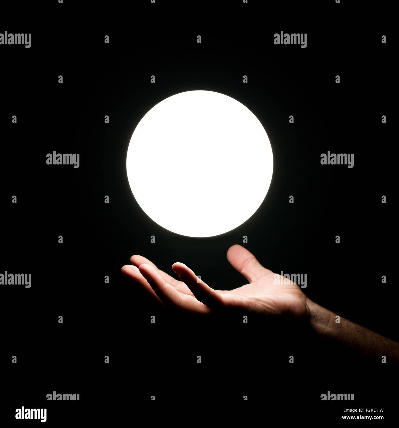 Bright light ball over human hand isolated on black background Stock Photo
