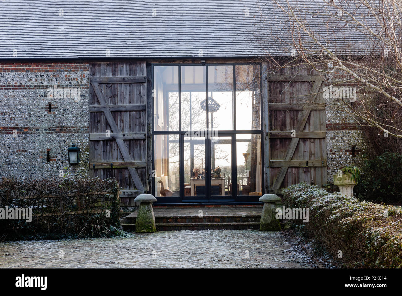 Vast glass doors and timber shutters at exterior of Sussex barn conversion Stock Photo
