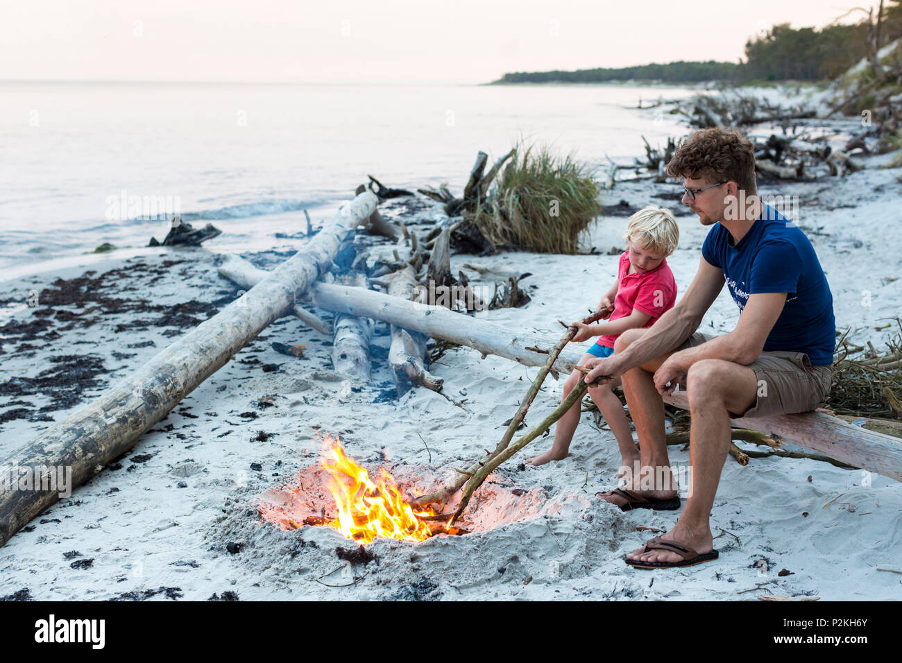 Five year old boy sitting with his father around a campfire, adventure, dream beach between Strandmarken und Dueodde, sandy beac Stock Photo