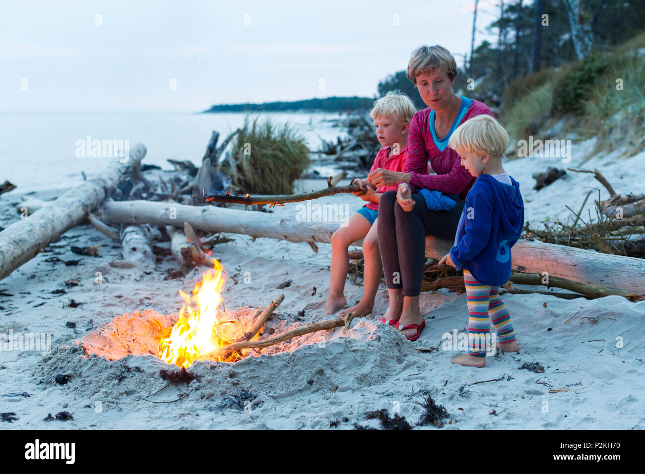 Familiy, mother and two children sitting around a campfire, adventure, dream beach between Strandmarken und Dueodde, sandy beach Stock Photo