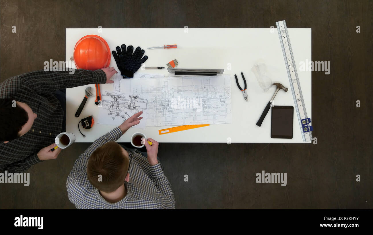 Two male architects discussing blueprints drinking coffee Stock Photo