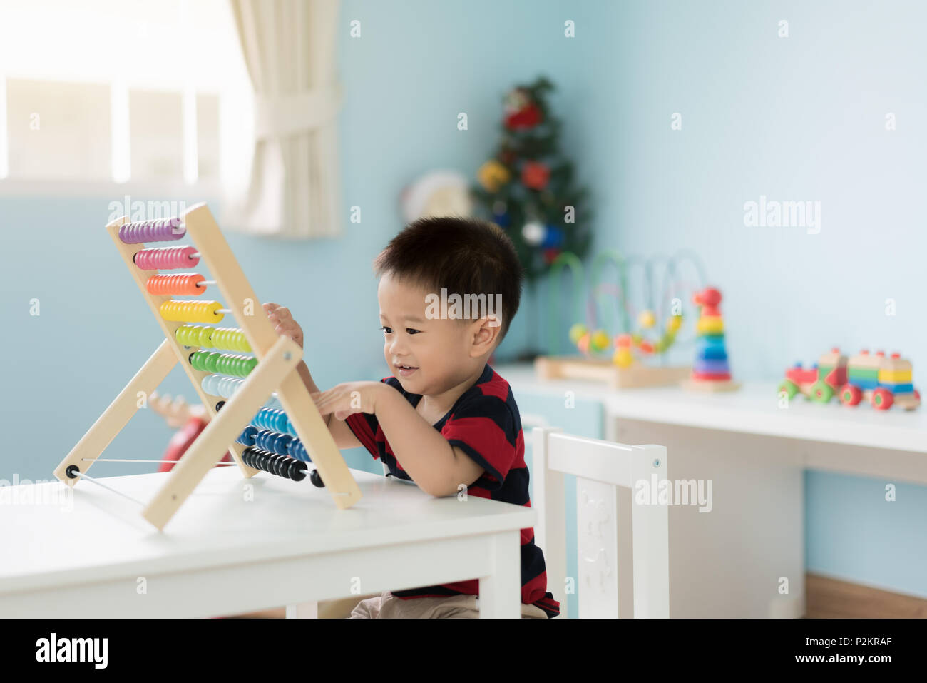 Asian Toddler baby boy learns to count. Cute child playing with abacus toy. Little boy having fun indoors at home. Educational concept for Toddler bab Stock Photo