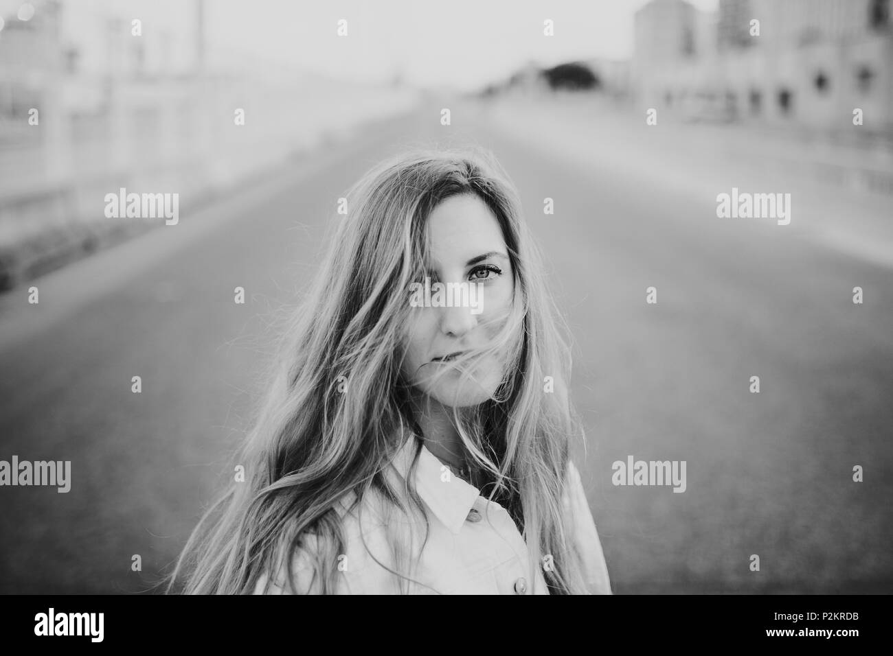 Black and white close up portrait of blonde woman posing in the middle of the road. Stock Photo