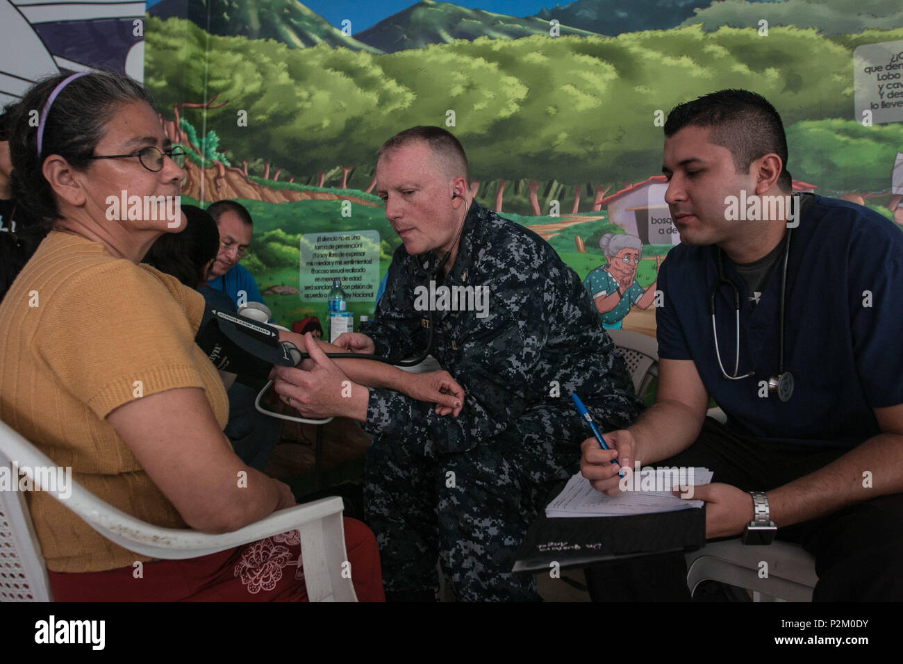 AHUACHAPAN, El Salvador (Sep. 8, 2016) - U.S. Navy Cmdr. Tony Silvetti, a gynecologist assigned to Naval Hospital Camp Lejeune, assists Dr. Angol Jose Gustavo M.D., a health worker with Operation Blessing’s Medical Brigade, check a patient’s vitals at a temporary treatment site in Ahuachapán, El Salvador during Southern Partnership Station 2016 (SPS-16).  Operation Blessing’s Medical Brigade is a non-for-profit mobile patient care unit established to provide medical service to those affected by natural disaster and render aid to rural areas. SPS-16 is an annual series of U.S. Navy deployments  Stock Photo