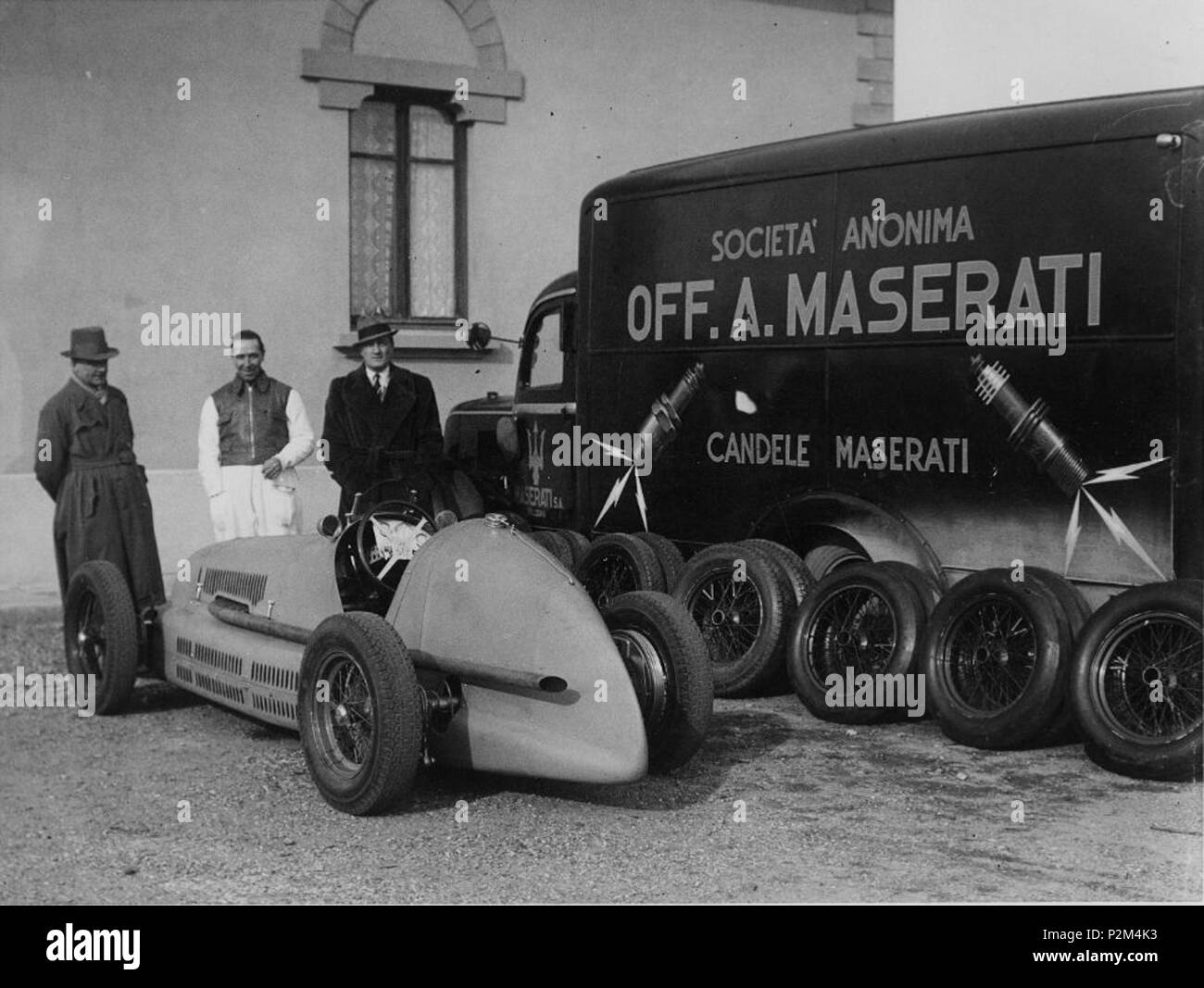 . English: Three men and a Maserati 4CL racecar, next to a company truck also advertising for Candele (spark plugs) by Maserati, which 1918 to 1960 also had an independent spark plug manufacturing company. Most likely, this is a pre-WWII picture, possibly from the launch of the 4CL at the end of the 1938 season. 1 April 2016. Unknown photographer 54 MaseratiCandele-truck Stock Photo